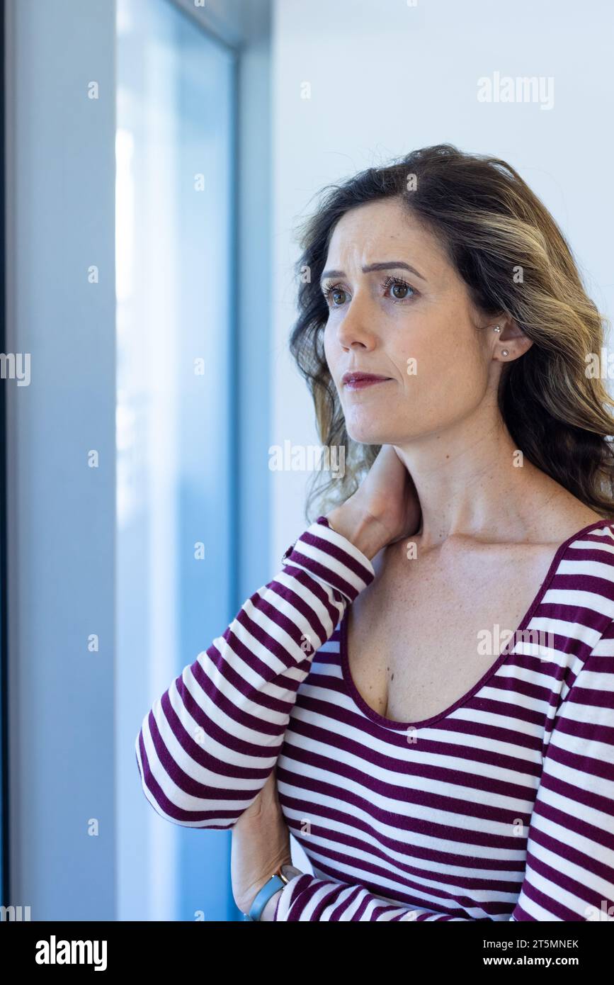 Besorgte kaukasische Mutter, die aus dem Fenster im Wartezimmer des Krankenhauses blickt Stockfoto