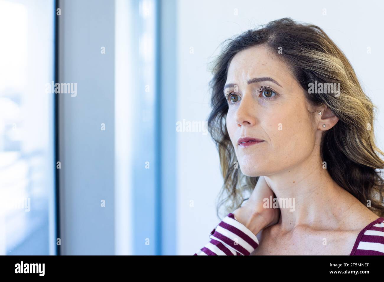 Besorgte kaukasische Mutter, die aus dem Fenster im Wartezimmer des Krankenhauses blickt, Kopierraum Stockfoto