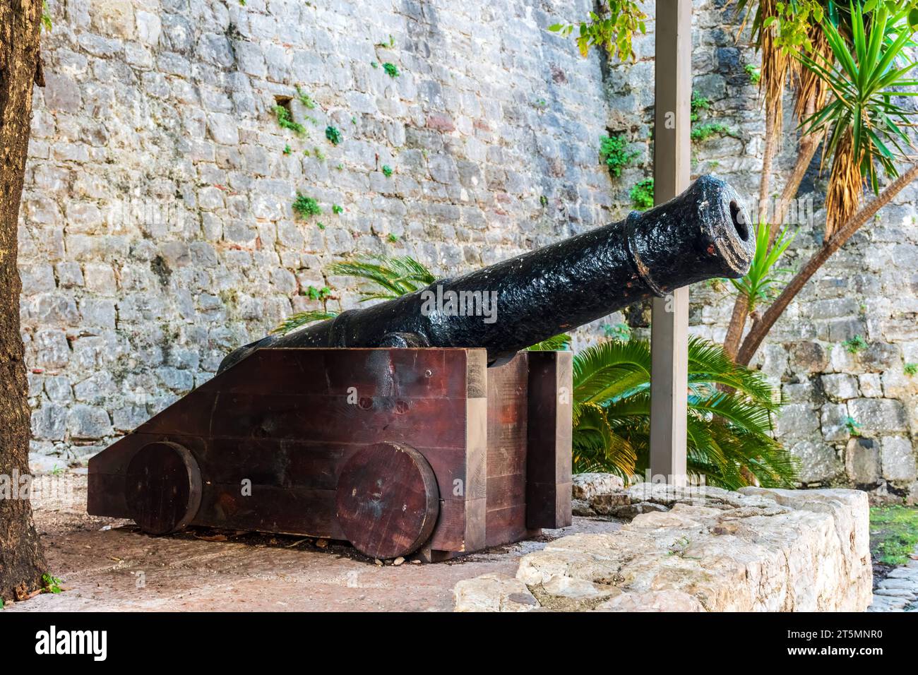 Mittelalterliche Kanone in der Altstadt von Budva, Montenegro. Gusseiserner Lauf auf einem Holzrahmen vor dem Hintergrund einer Steinmauer in Stari Grad montiert Stockfoto