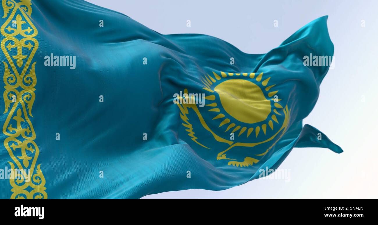 Nahaufnahme der kasachischen Nationalflagge, die an einem klaren Tag winkt. Hellblaues Feld mit einer gelben Sonne und fliegendem Adler in der Mitte und einem gelben Zierwerk Stockfoto