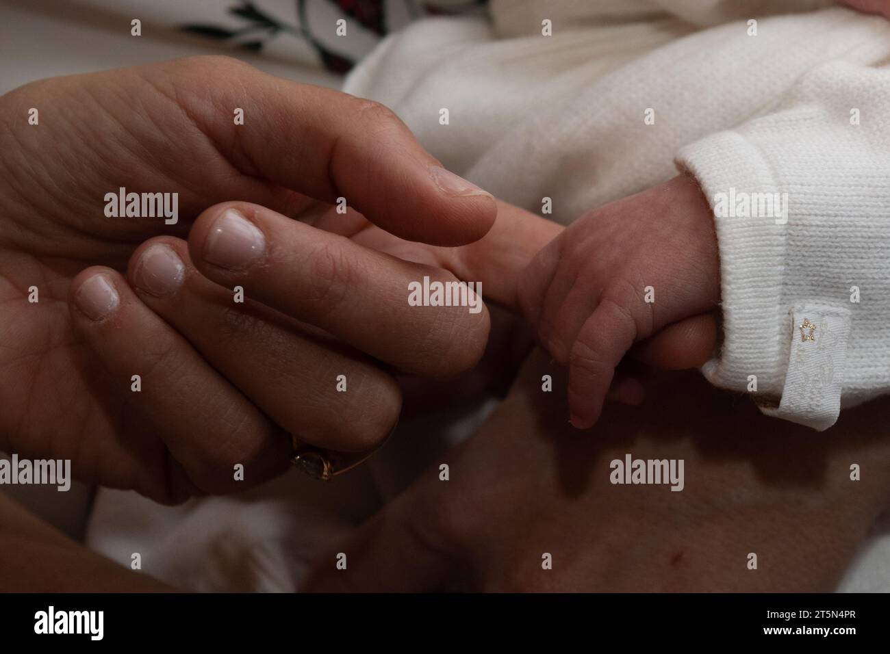 Die winzige Hand eines Neugeborenen reicht aus und greift den gestreckten Finger der Hand eines erwachsenen Mannes. Stockfoto