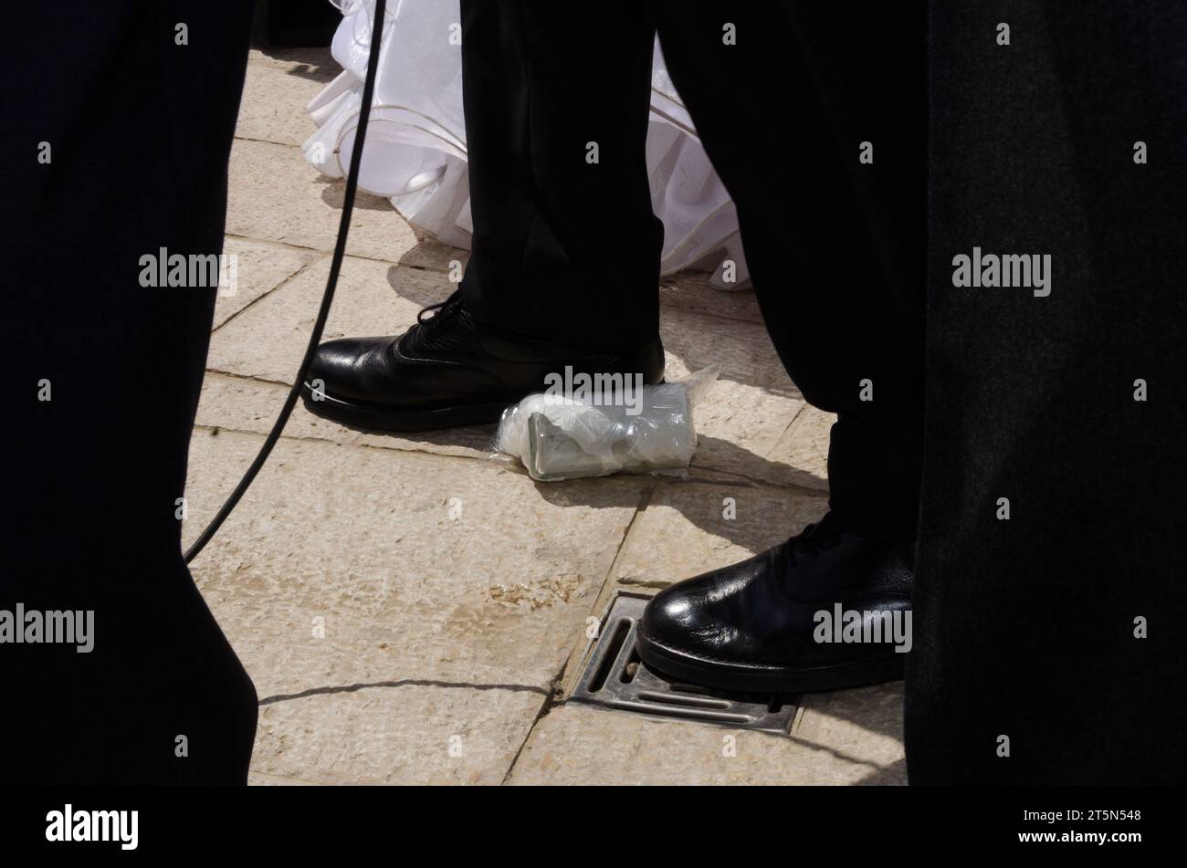 Ein Bräutigam tritt auf und bricht ein Glas, Teil einer Tradition während einer jüdischen Hochzeitszeremonie. Stockfoto