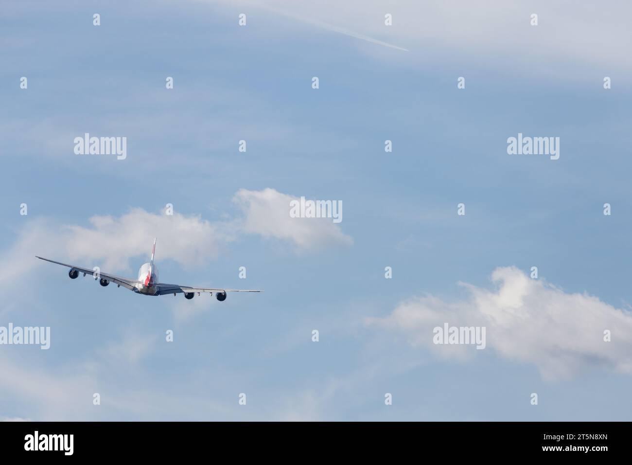 British Airways Airbus A380-841, G-XLEF verlässt London Heathrow in den sonnigen Nachmittag. Ein Kondensstreifen ist von einem anderen Flugzeug aus in der Entfernung sichtbar Stockfoto