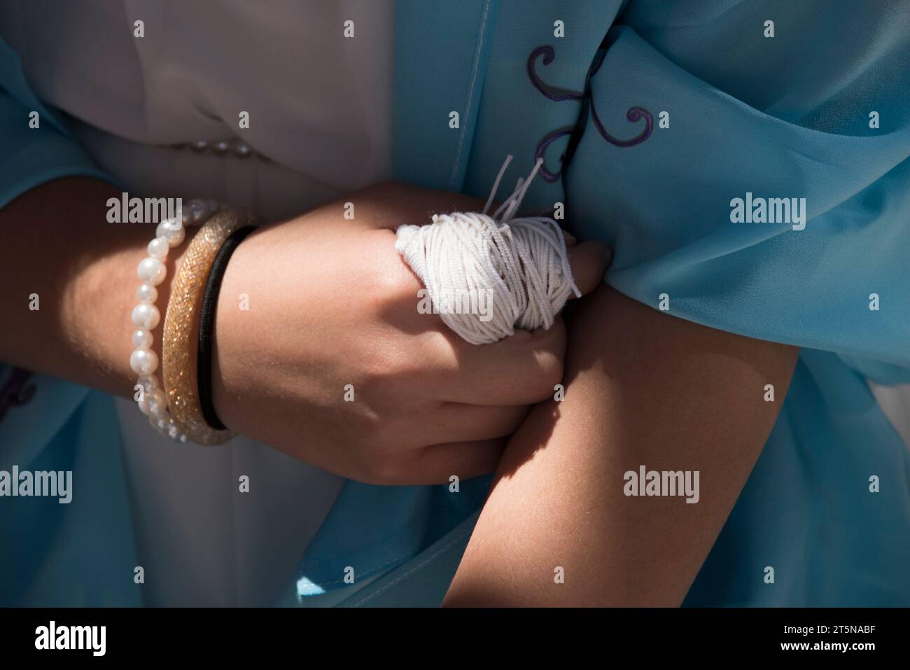 Eine jüdische Frau, die ihre bat Mizwa feiert, greift die Fäden ihres Tallit oder Zitzits, während sie das Schema Jisrael-Gebet rezitiert. Stockfoto