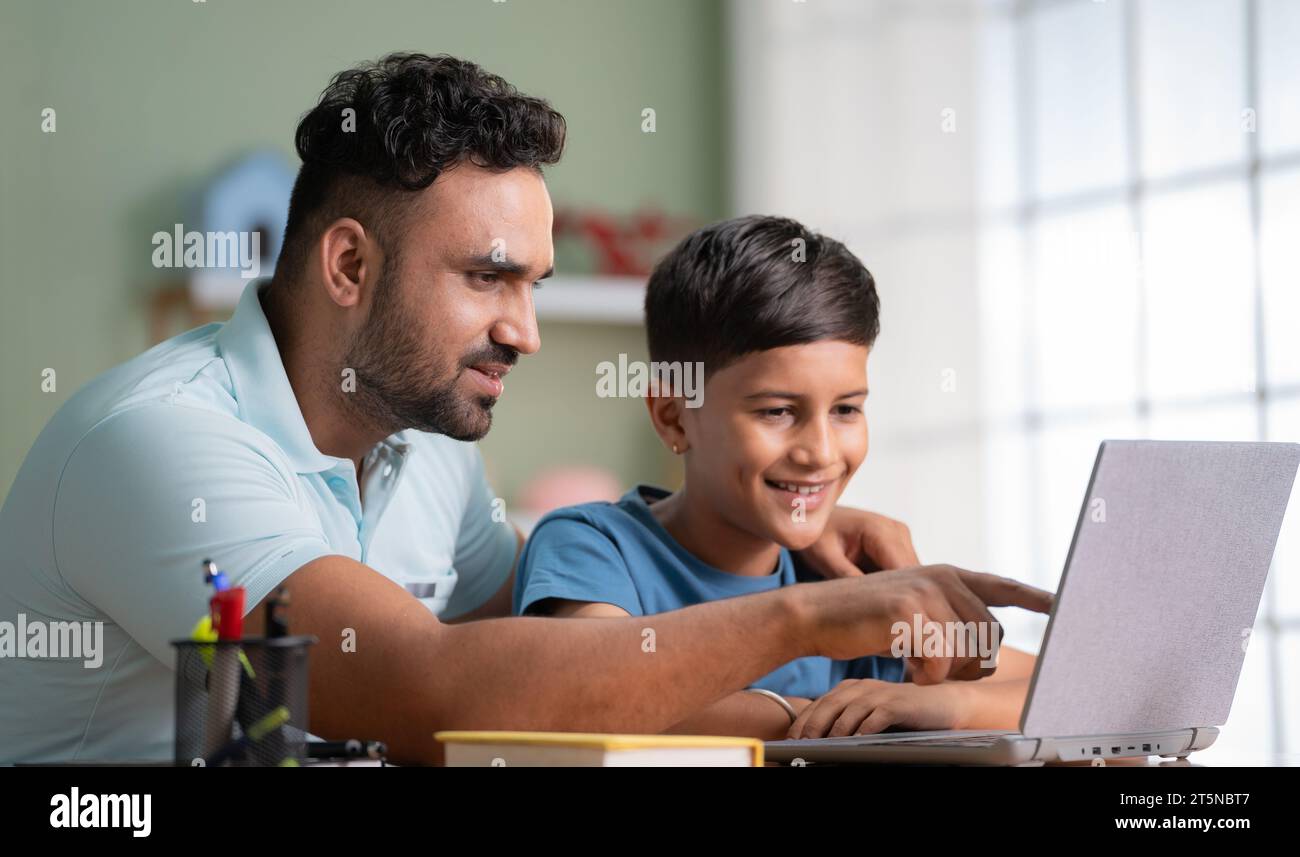 Indischer Vater erklärt oder unterrichtet vom Laptop bis zum Sohn zu Hause - Konzept von Familienunterstützung, Heimunterricht und Hausaufgaben-Unterstützung Stockfoto