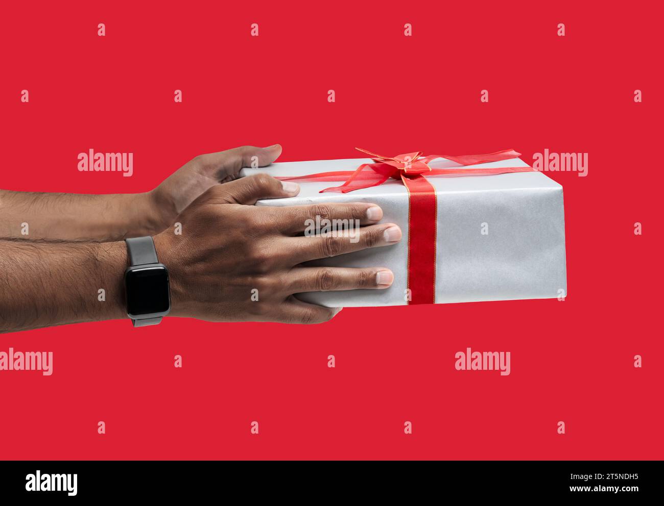 Hand eines Afro-Mannes, der eine Geschenkbox über isoliertem roten Hintergrund hält. Stockfoto