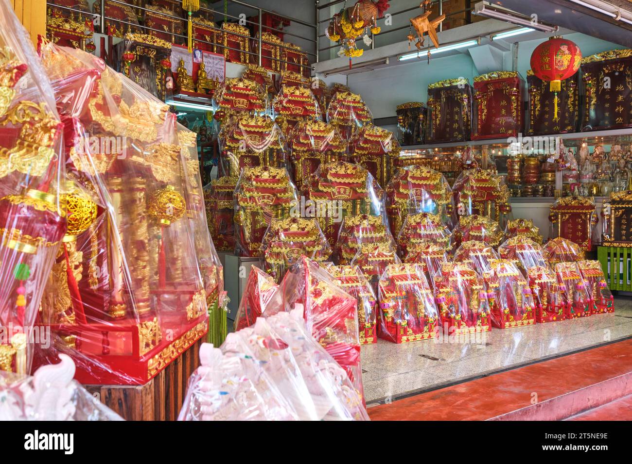 Eine große Auswahl an gewickelten roten und goldenen Mini-buddhistischen Hausaltertümern zum Verkauf. An einer religiösen Ikone, Reliquienladen entlang der Bamrung Mueang Road in Bangkok, Thai Stockfoto