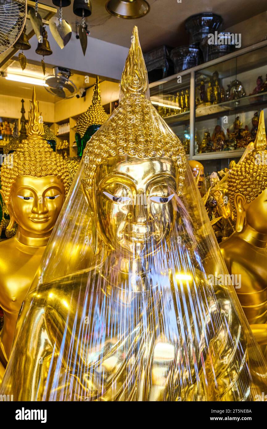 Eine Gruppe großer, goldener Buddhas zum Verkauf. An einer religiösen Ikone, einem Reliquienladen entlang der Bamrung Mueang Road in Bangkok, Thailand. Stockfoto