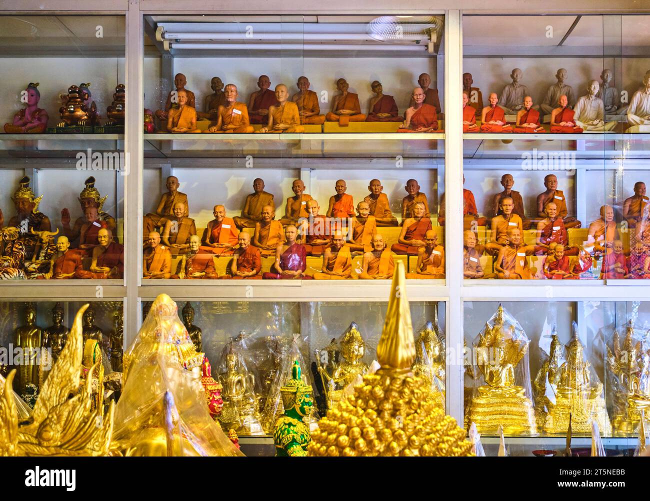 Eine große Auswahl an kleinen, sitzenden Mönchstatuen von echten Mönchen zum Verkauf. An einer religiösen Ikone, Reliquienladen entlang der Bamrung Mueang Road in Bangkok, Thailan Stockfoto