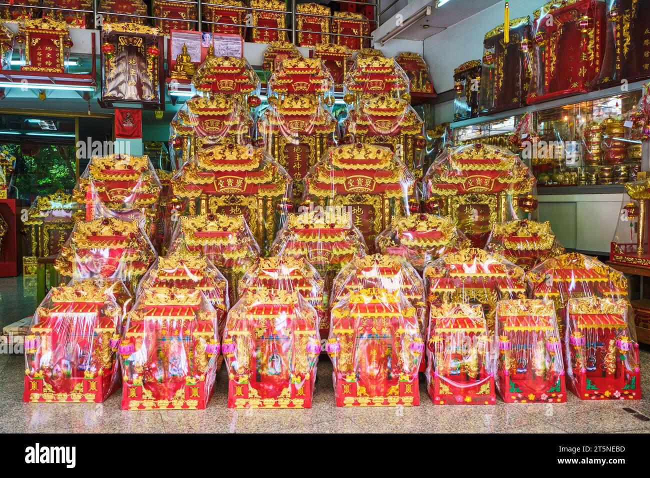 Eine große Auswahl an gewickelten roten und goldenen Mini-buddhistischen Hausaltertümern zum Verkauf. An einer religiösen Ikone, Reliquienladen entlang der Bamrung Mueang Road in Bangkok, Thai Stockfoto