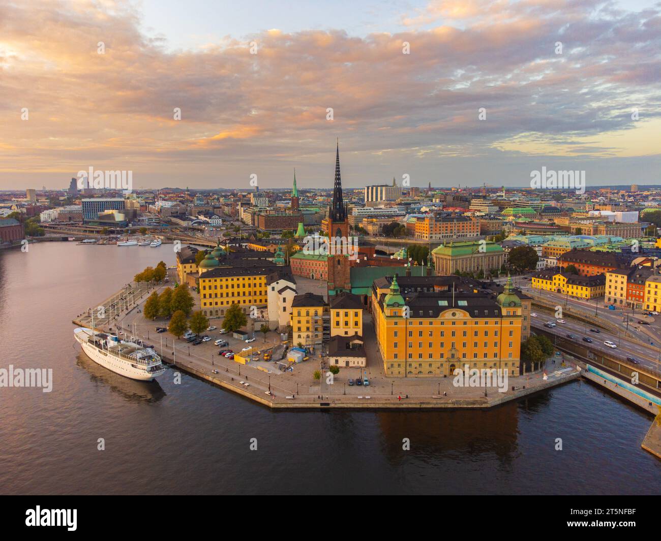 Panoramablick auf Stockholm, mit Riddarholmen und Kungsholmen, bei Sonnenuntergang im Herbst. Teilweise bewölkter Himmel, rosa Wolken. Riddarholmen Kirche. Boot angedockt. Stockfoto