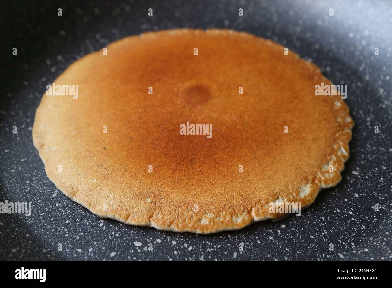 Nahaufnahme eines fast fertig gebratenen Pfannkuchens in der Pfanne Stockfoto