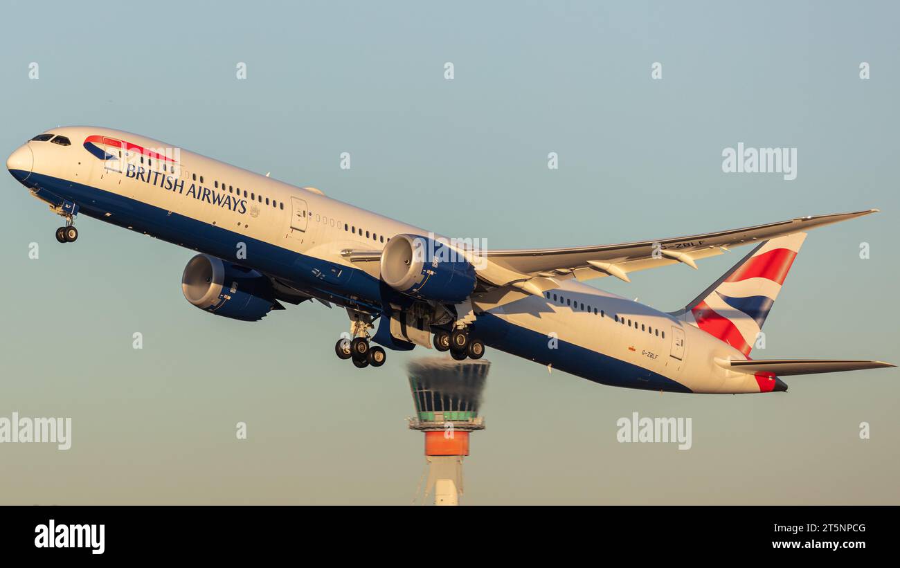 Eine British Airways Boeing 787-10 Dreamliner mit der Registrierung G-ZBLF verlässt London Heathrow (lhr) an einem sonnigen Herbstabend mit dem ATC-Turm hinter sich Stockfoto