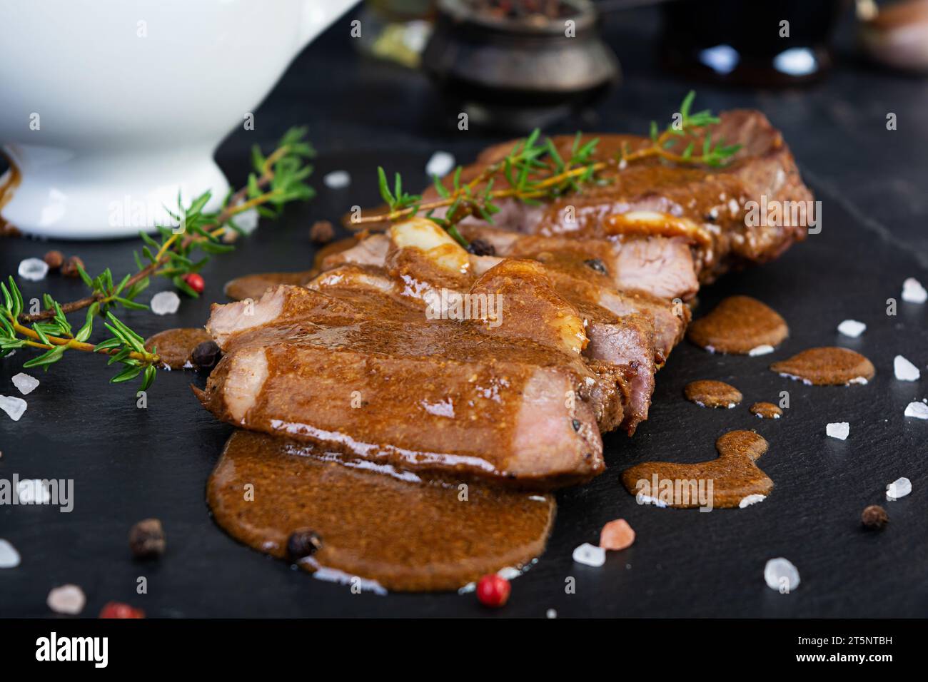 Gegrilltes Rindersteak mit Kräutern und Gewürzen auf Steinplatte Stockfoto