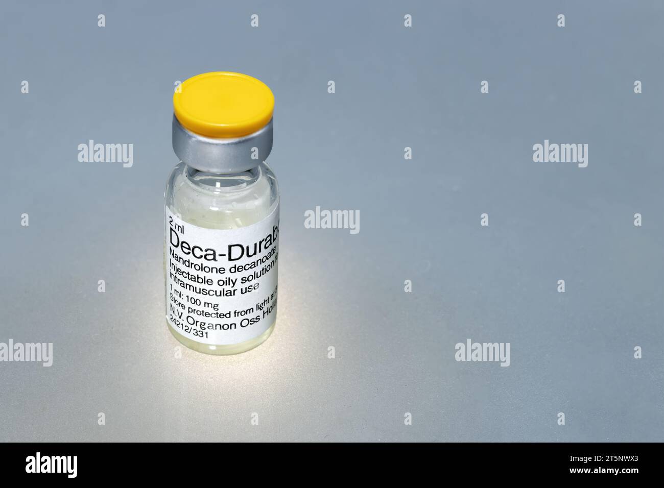 Spanien, Madrid, 01-13-2022, Eine Durchstechflasche mit flüssiger Substanz zu injizieren, ein anaboles Steroid namens Nandrolon Decanoate auf grauem Hintergrund Stockfoto