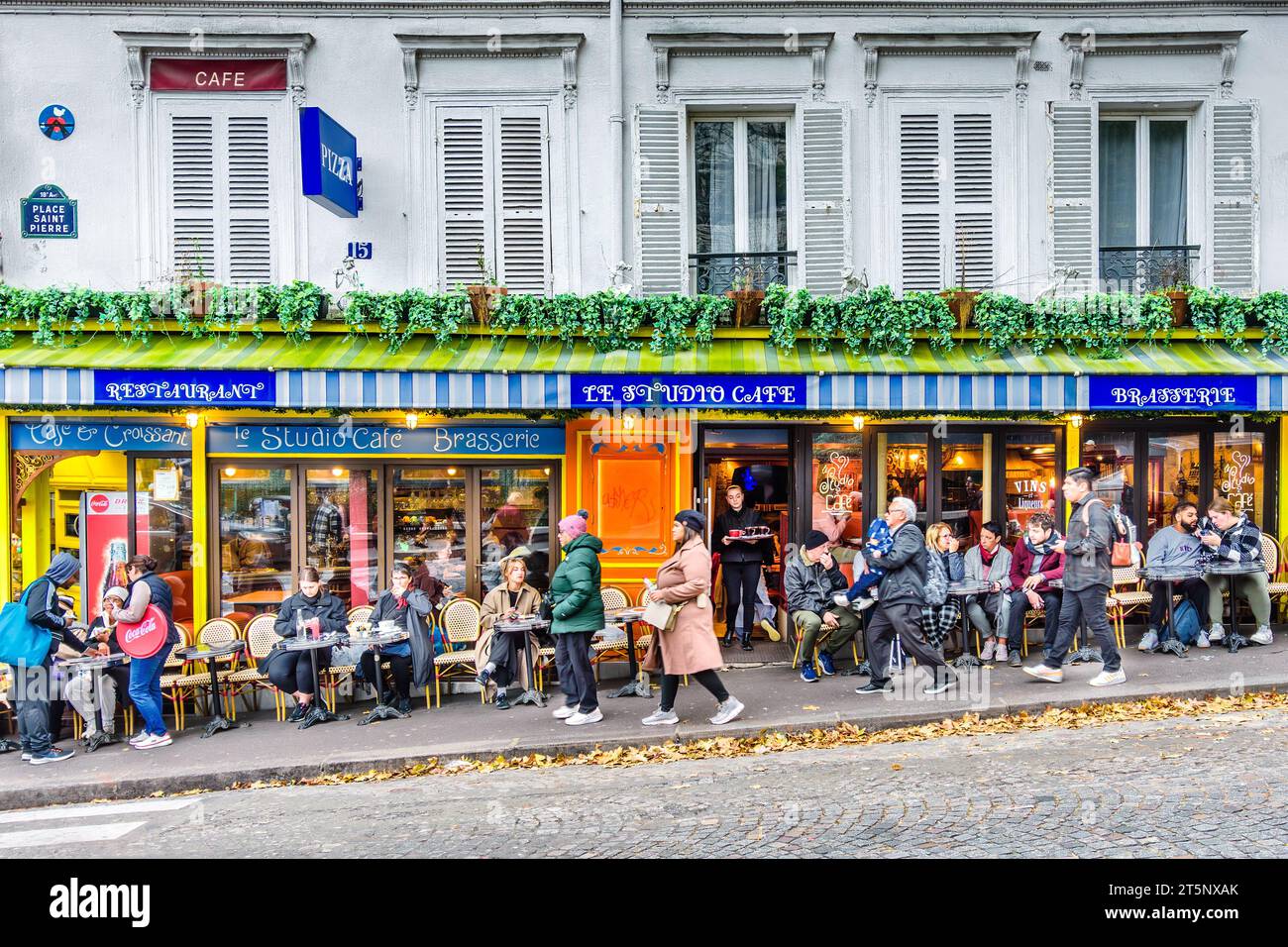 Touristen im beliebten "Le Studio Cafe" mit Blick auf Sacre-Coeur am Place Saint-Pierre, Montmartre, Paris 18, Frankreich. Stockfoto