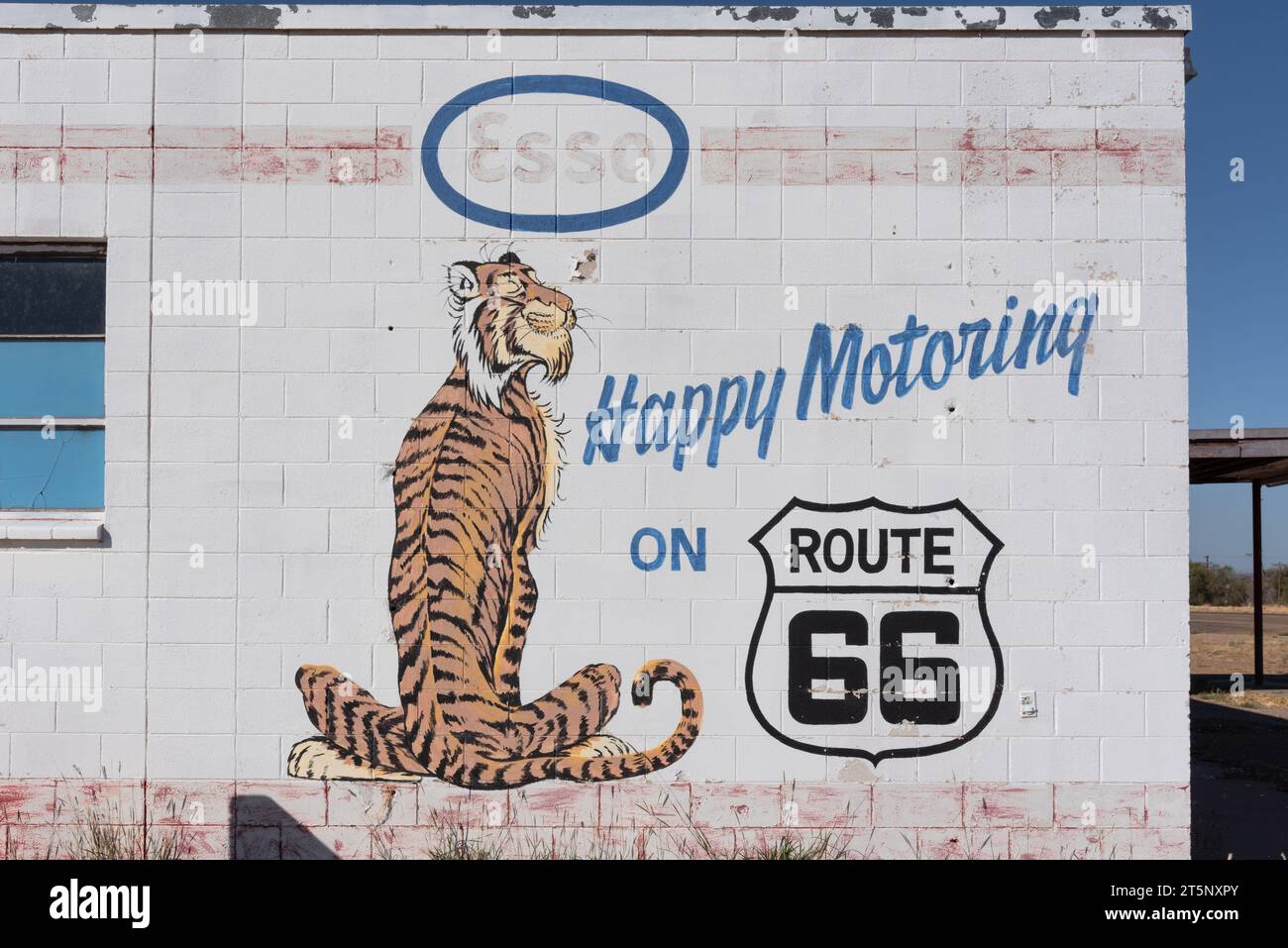 Seite des alten Esso-Bahnhofs, jetzt leer, an der Route 66, ein Cartoon-Tiger auf der Seite gemalt und sein Slogan Happy Motoriing, Tucumcari, New Mexico, USA. Stockfoto