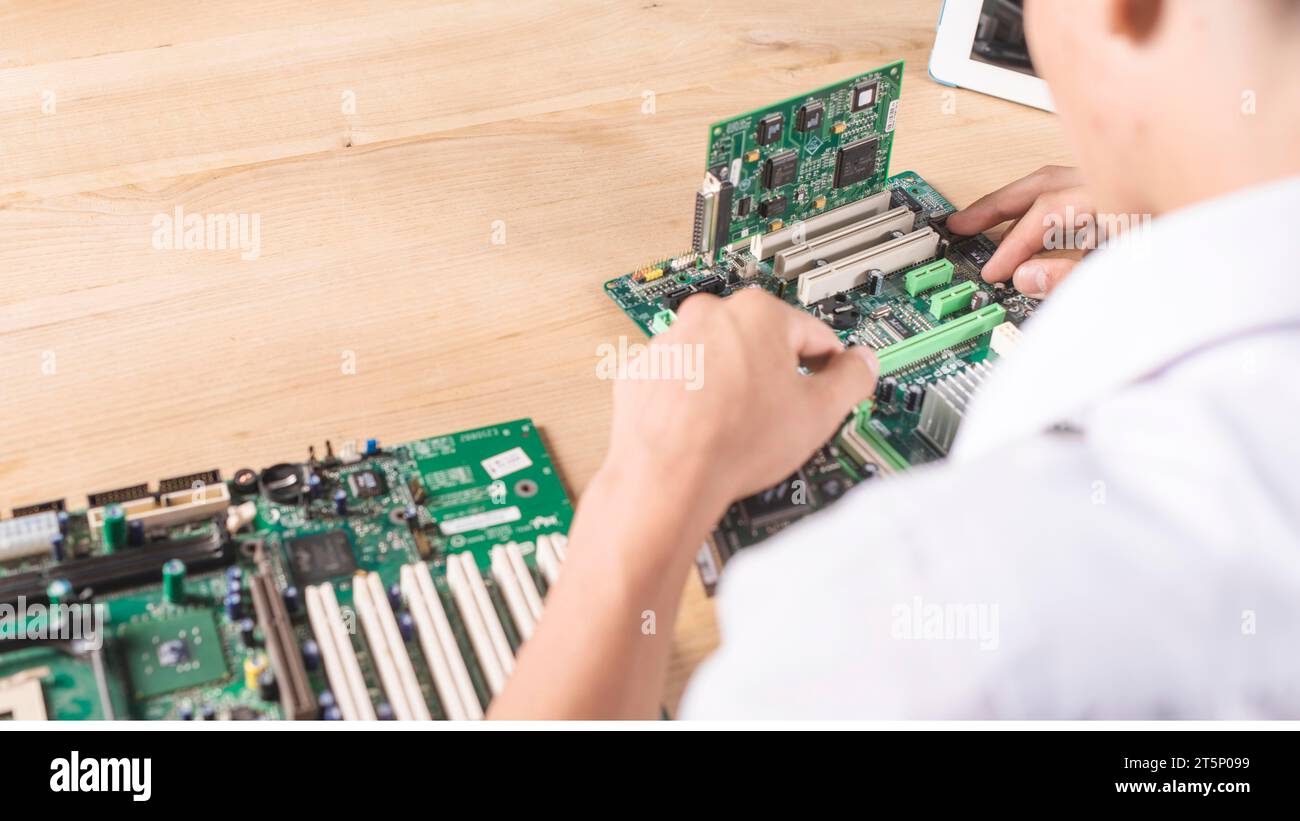 Nahaufnahme männlicher Techniker, der modernen pc-Motherboard Holztisch repariert Stockfoto