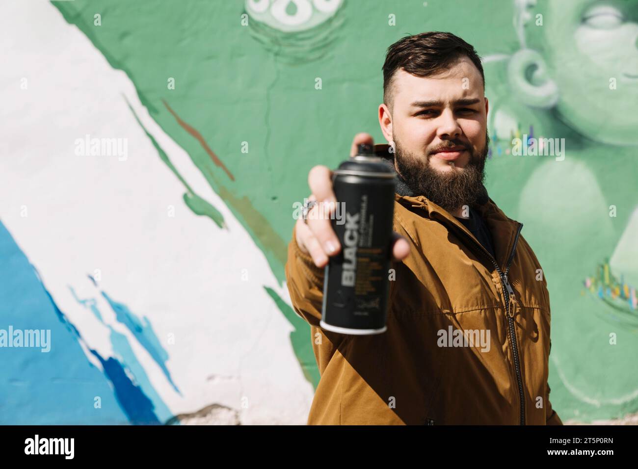 Mann steht vorne Graffiti-Wand mit Aerosol-Dose Hand Stockfoto