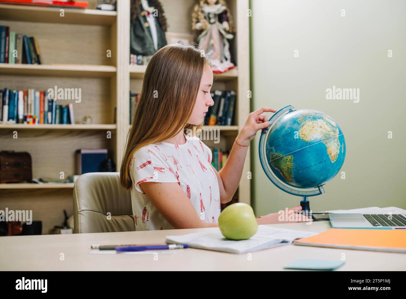 Der Schüler posiert auf dem Globus-Tisch Stockfoto