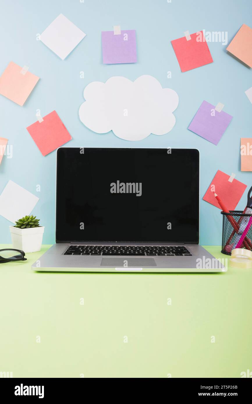 Wand mit Cloud-Papier Klebenotizen Laptop mit leerem schwarzen Bildschirm Stockfoto
