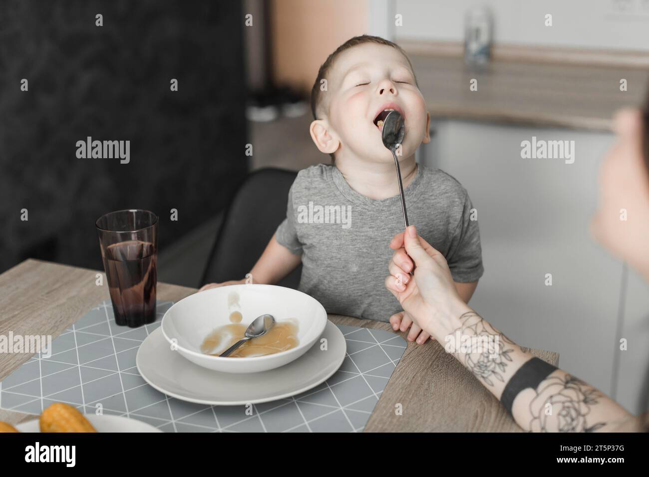Nahaufnahme Junge mit geschlossenen Augen, lecken Löffel von seiner Mutter Stockfoto