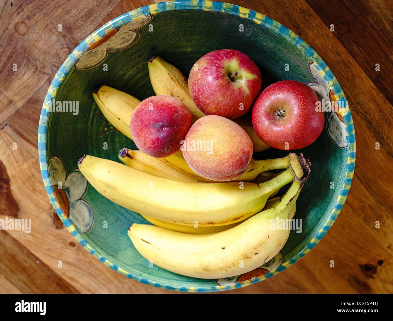 Eine Töpferschale mit Obst: Äpfel, Bananen. Pfirsiche Stockfoto