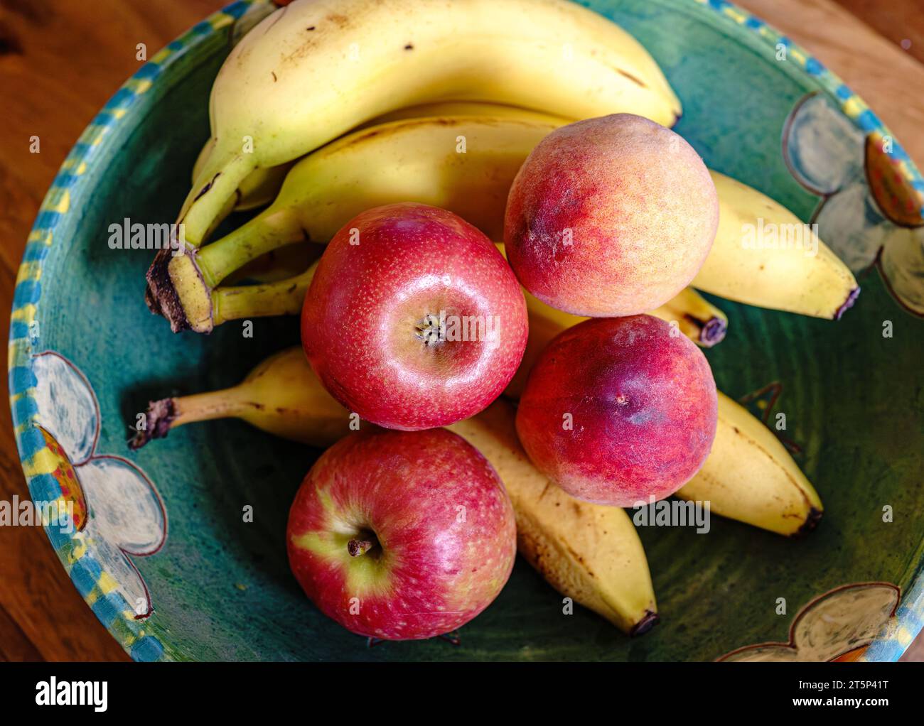 Eine Töpferschale mit Obst: Äpfel, Bananen. Pfirsiche Stockfoto