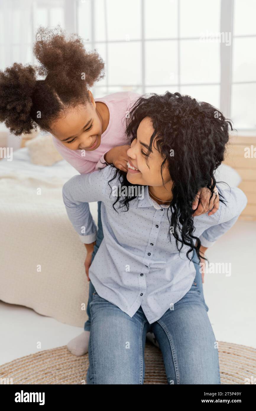 Smiley-Mutter mit Vorderansicht, die mit ihrer Tochter zu Hause spielt Stockfoto