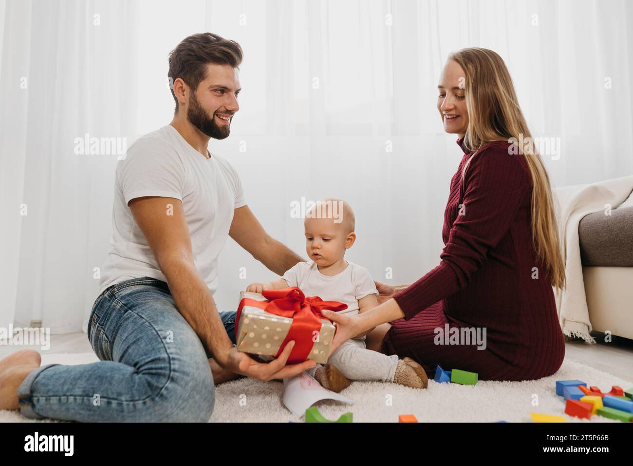 Eltern mit seitlichem Blick zu Hause mit ihrem Babygeschenk Stockfoto