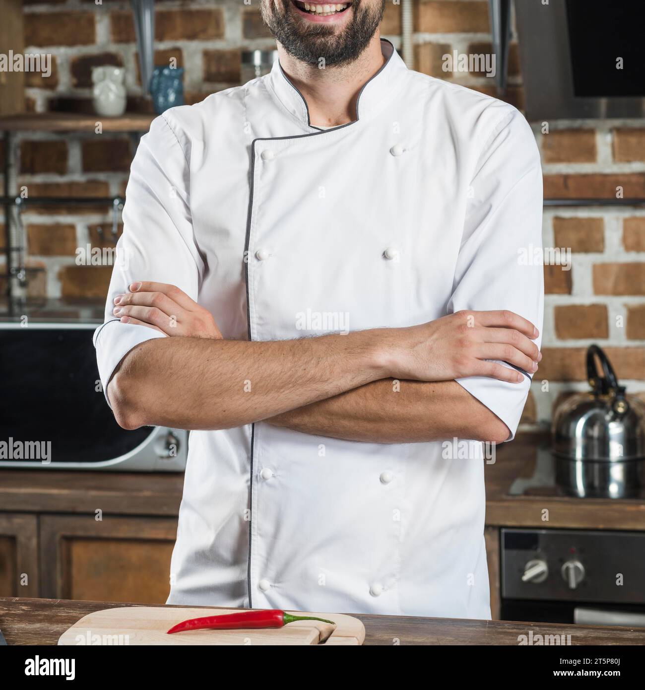 Nahaufnahme männlicher Koch mit überkreuztem Arm, stehende Küchenzeile Stockfoto