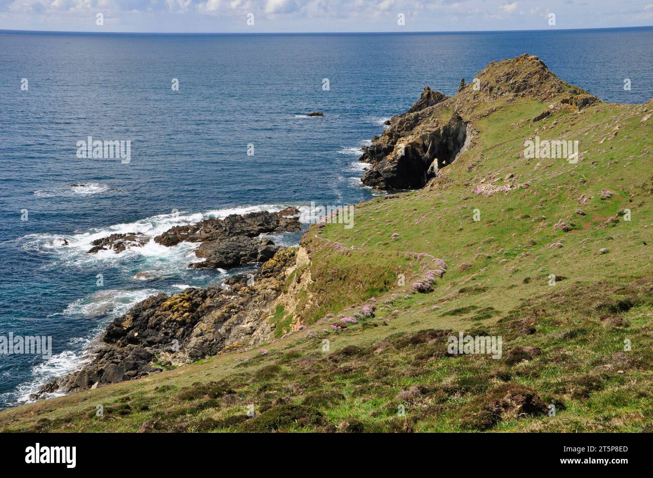 An einem hellen Frühlingstag schlängelt sich das kristallblaue Meer sanft auf den Granitfelsen von Cudden Point in der Nähe der Preußischen Bucht in Cornwall. Stockfoto