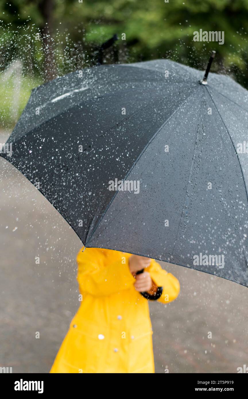 Kleines Kind mit großem schwarzen Regenschirm Stockfoto