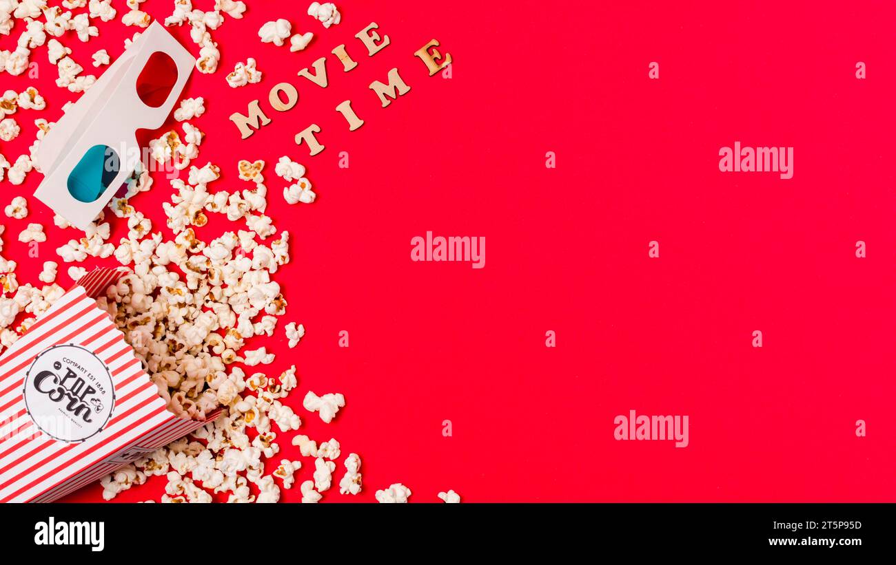 Text zur Filmzeit mit 3D-Brille verschütteter Popcorn-roter Hintergrund Stockfoto