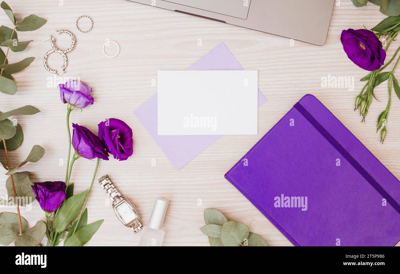 Lila Eustoma Blumen Ohrringe Tagebuch Armbanduhr nagellack Holzschreibtisch Stockfoto