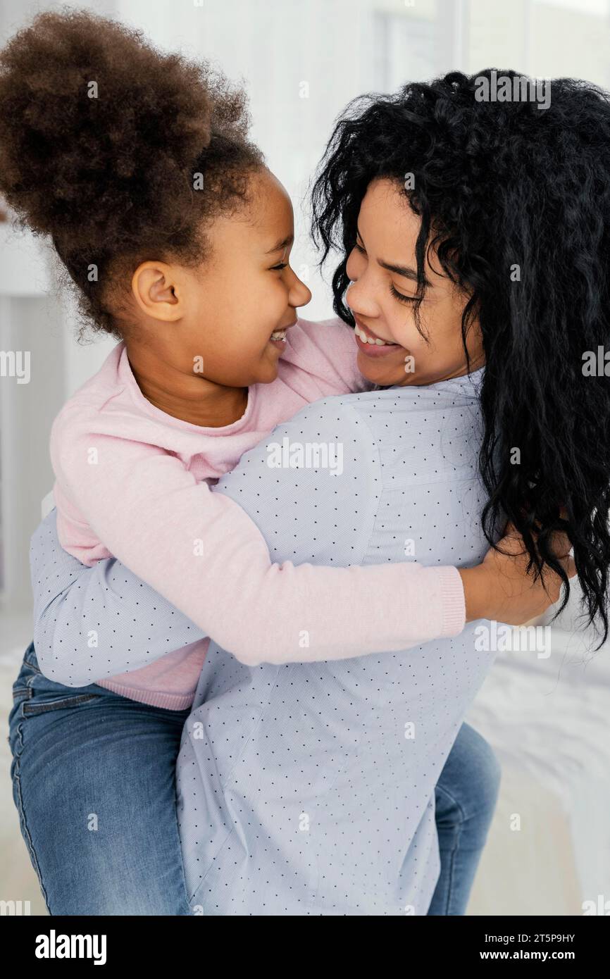 Seitliche Ansicht, glückliche Mutter hält ihre lächelnde Tochter Stockfoto