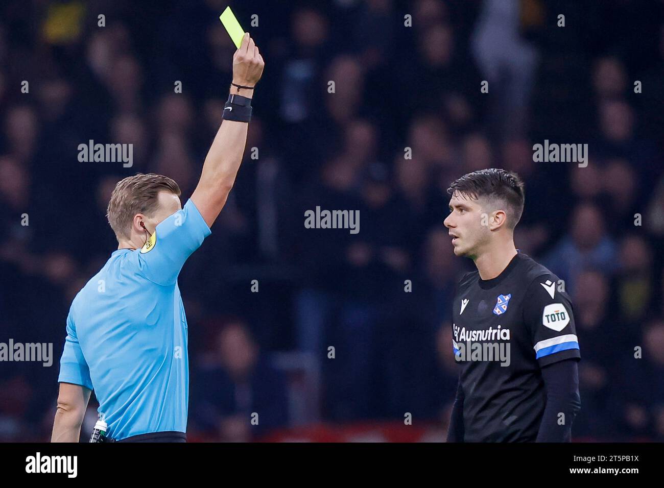 AMSTERDAM, NIEDERLANDE - 5. NOVEMBER: Schiedsrichter Sander van der Eijk und Pelle van Amersfoort (SC Heerenveen) zeigen die gelbe Karte während der Eredivisie Stockfoto