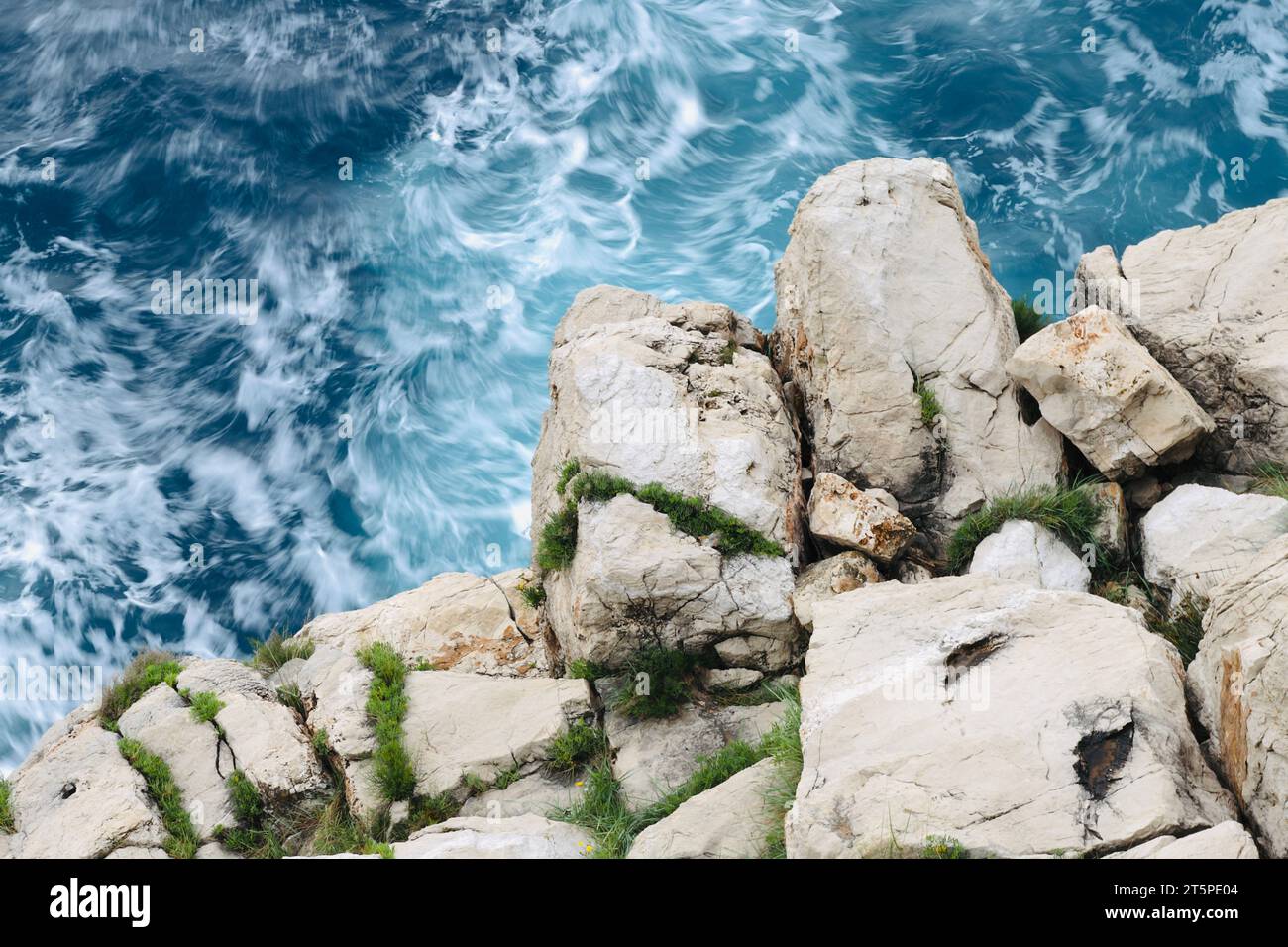 Weiße felsige Klippe mit wavey blauem Meerwasserhintergrund Stockfoto