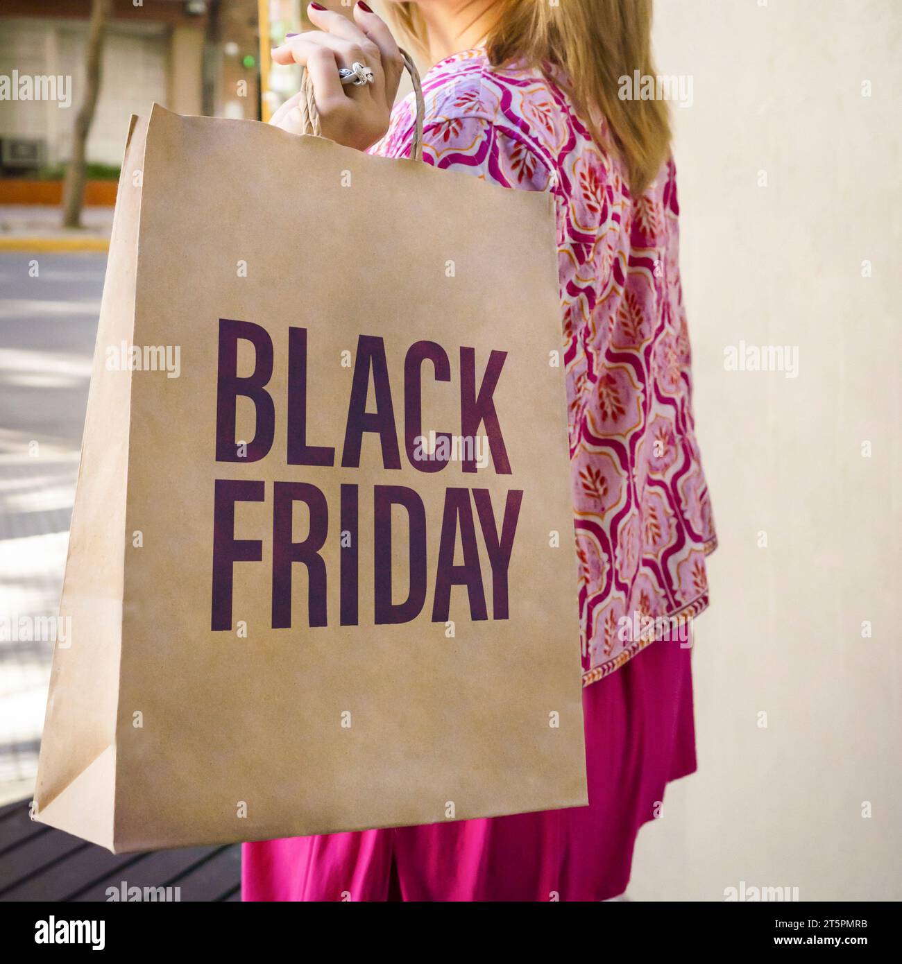 Nahaufnahme einer Einkaufspapiertüte mit einem Black Friday Schild, getragen von einer Frau Stockfoto