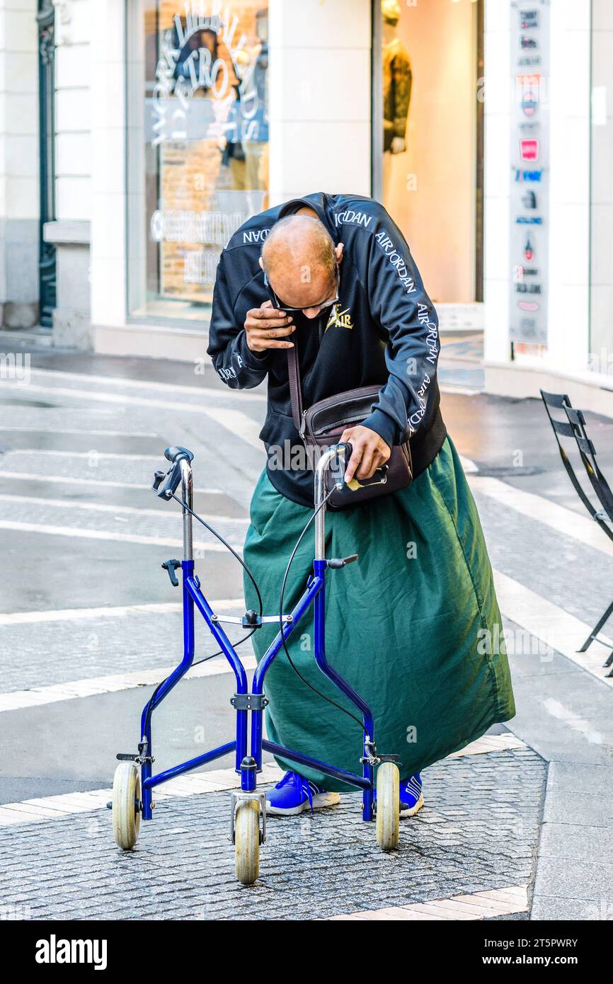 Behinderter Mann mit Gehhilfe und telefonischem Sprechen - Tours, Indre-et-Loire (37), Frankreich. Stockfoto