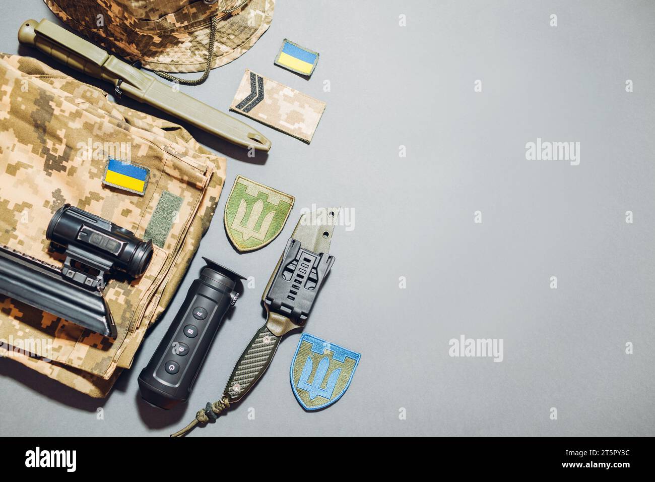 Ukrainische Militärausrüstung flach gelegt Hintergrund. Militäruniform, Accessoires, Wärmebildkamera, Munition, Messer mit Nationalflaggen und EM Stockfoto
