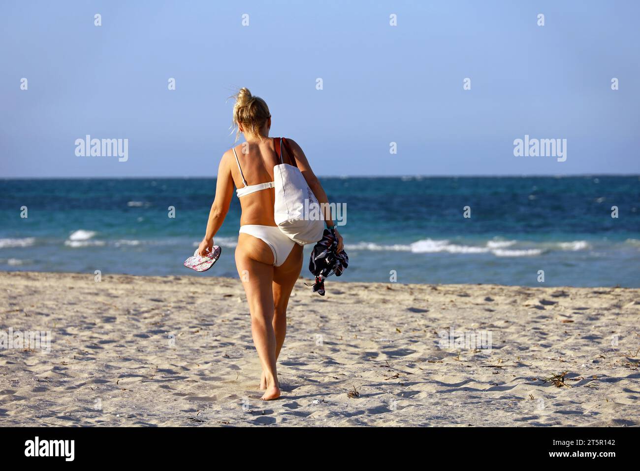 Barfuß Frau in weißem Bikini, die am Strand am Strand entlang läuft. Ozeanküste, Touristenresort Stockfoto