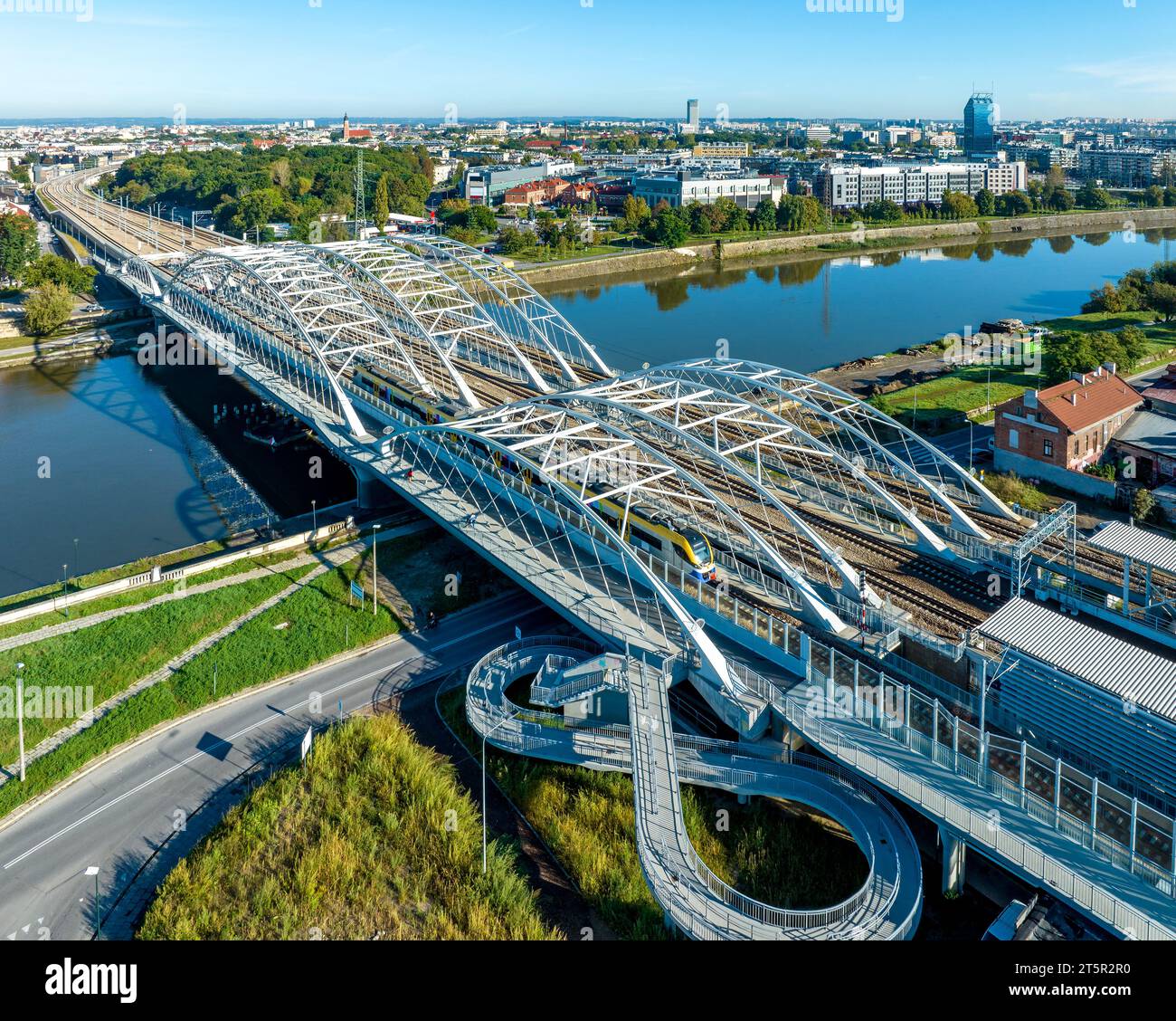 Schneller Stadtzug auf der neuen dreigleisigen Bahnbrücke mit vier Gleisen, Fußgängerbrücke und Radweg über die Weichsel in Krakau, Polen, in die neue K Stockfoto