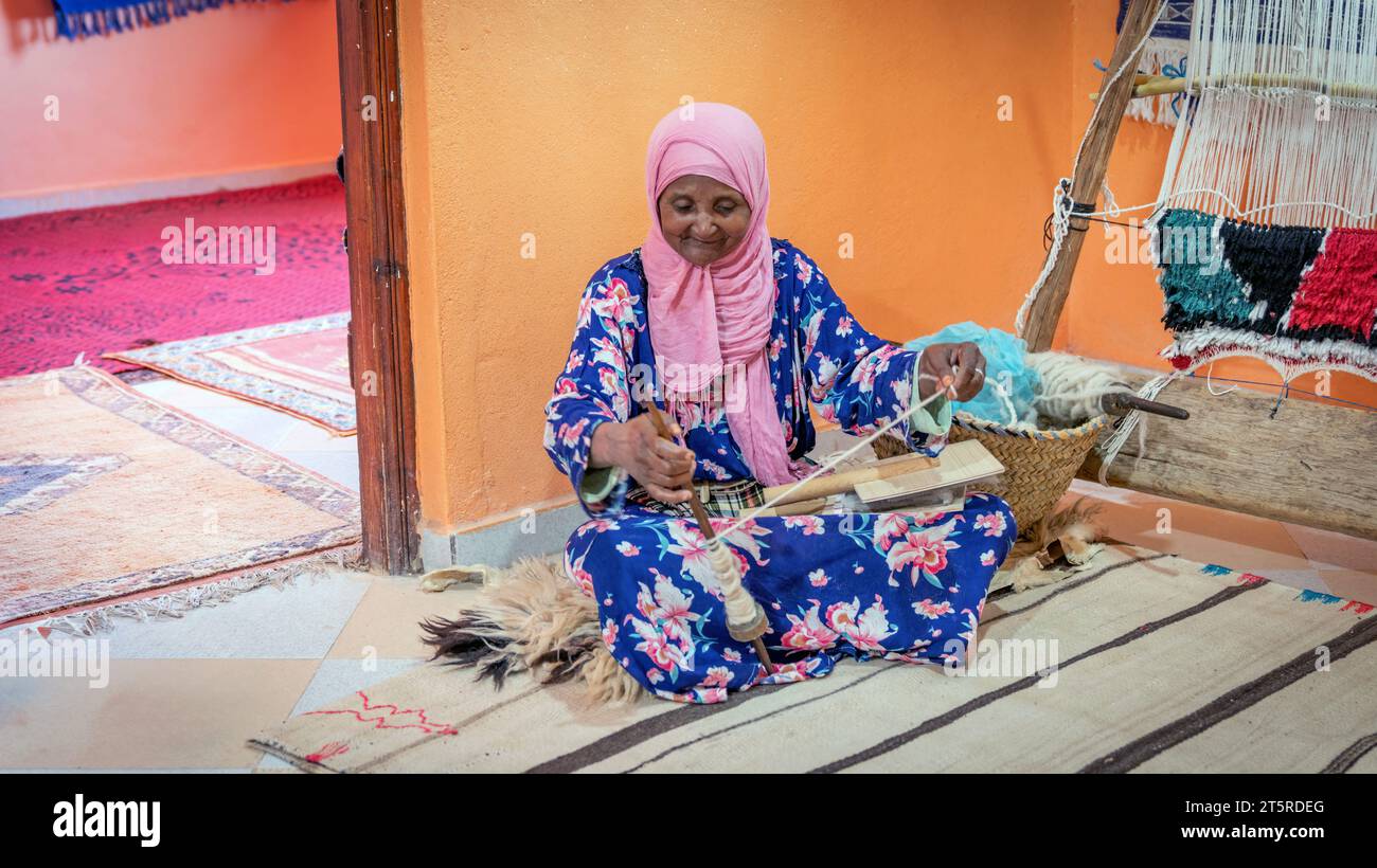 Fes, Marokko - 14. September 2022: Ältere Frau, die eine Wollschnur für einen marokkanischen Teppich spinnt. Ein marokkanischer Teppich ist ein handgewebtes Meisterwerk, gefertigt von Stockfoto