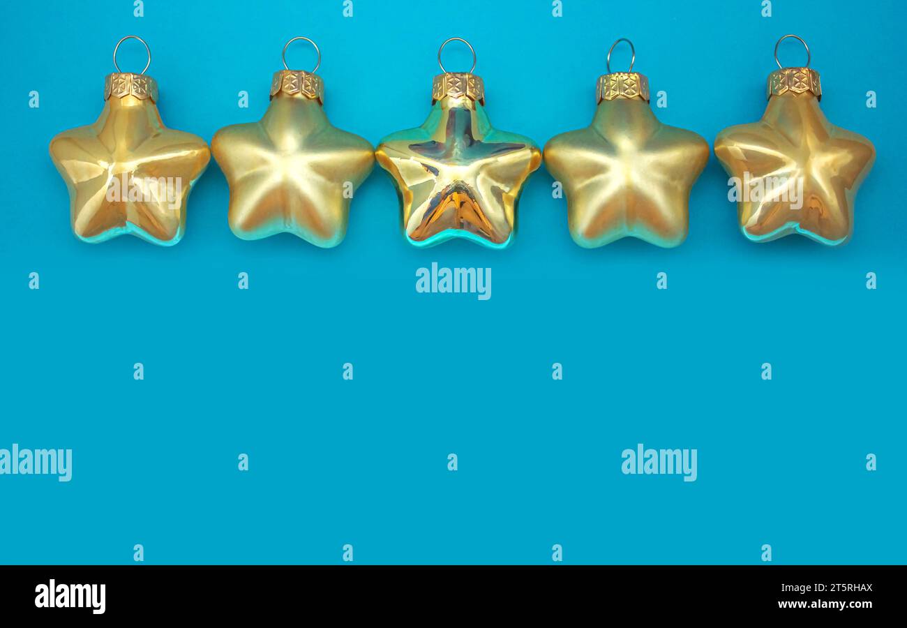 Fünf goldene Weihnachtsschmuck mit fünf Punkten. Goldene Kugeln auf blauem Hintergrund mit Kopierraum. Weihnachtliche Dekoration, festliche Atmosphäre. Stockfoto