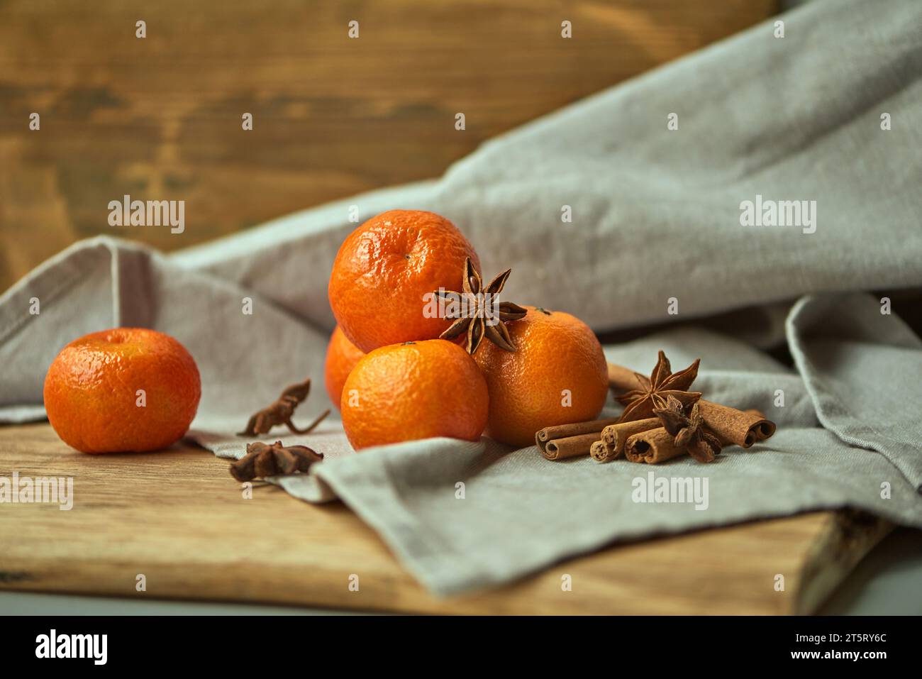 Frische Mandarinen, Zimtstangen und Sternanis sind auf einer Leinentischdecke angeordnet. Zutaten für Weihnachtsgetränke. Stockfoto