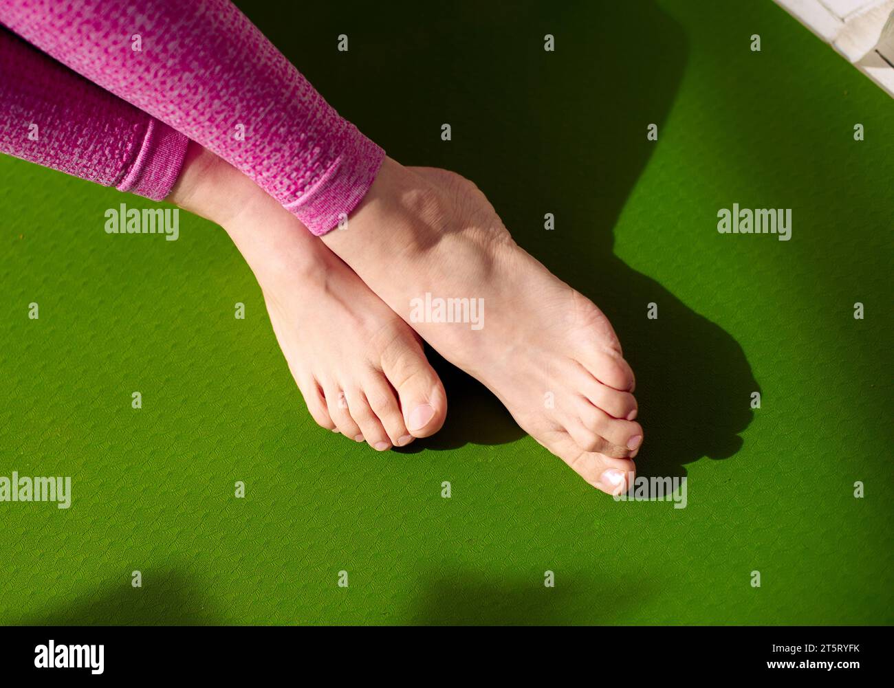 Nach einer Massage, um Muskelstress zu lindern, entspannen sich die Füße einer Frau auf einer grünen Yogamatte. Verringerung von Muskelkater, Erhöhung des Blutflusses. Ph Stockfoto