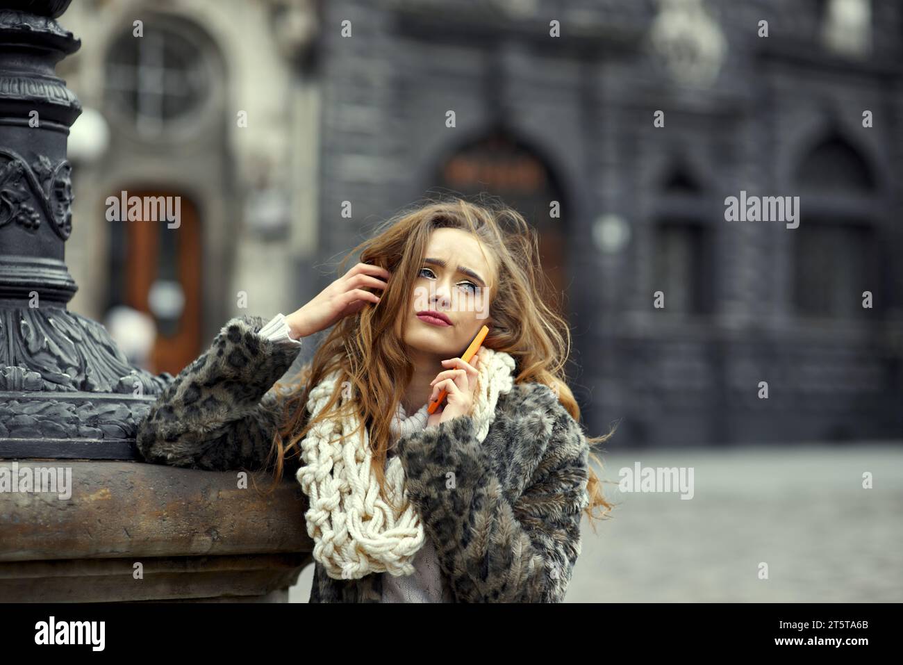 Ein schönes junges Mädchen mit voluminösen Haaren hört sich ein langweiliges Gespräch eines Mobilfunkanbieters an, schreibt Notizen von ihren Eltern oder ist über ein negatives Verhalten verärgert Stockfoto