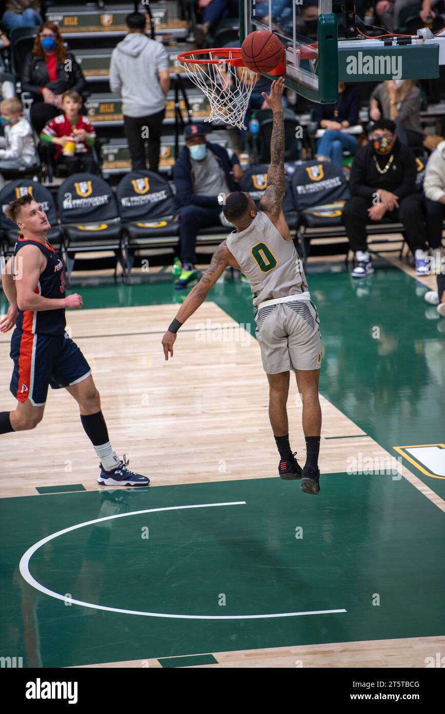 College-Basketballspieler, der während der NCAA-Action einen Layup am Rand beendet, werden mit scharfen Details und dynamischen Bewegungen auf dem Hallenplatz erfasst. Stockfoto