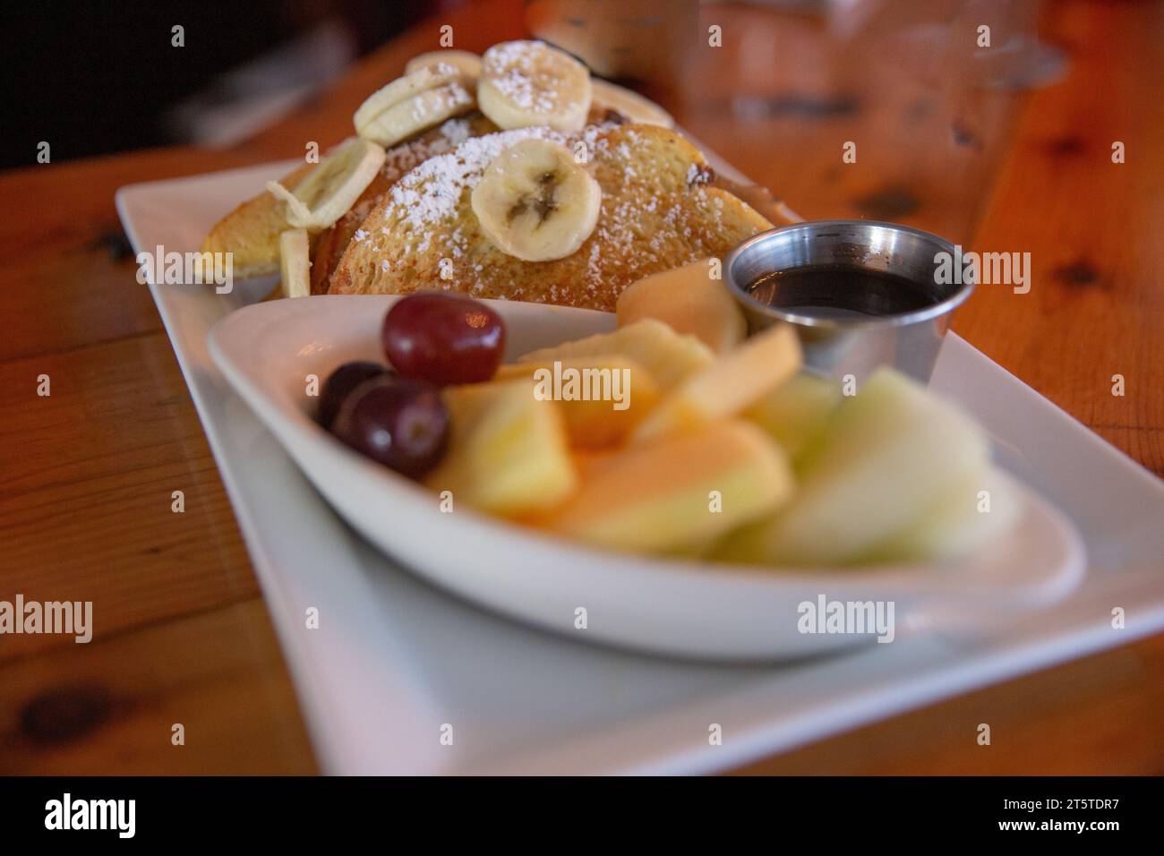 Bananen-French-Toast-Mahlzeit serviert mit Sirup und Beeren Stockfoto